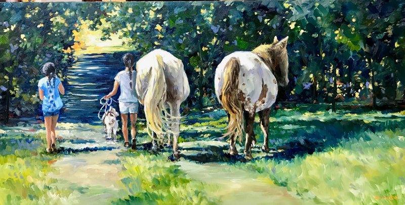 Two people walking with two horses on a path surrounded by trees