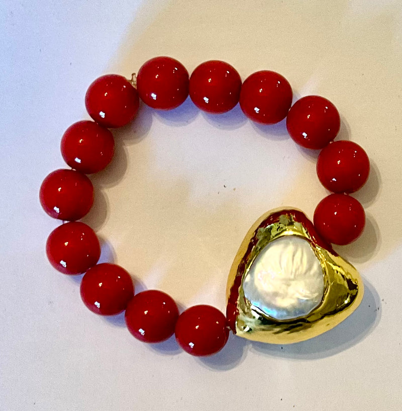 Bracelet with red beads and a gold heart clasp on a white background