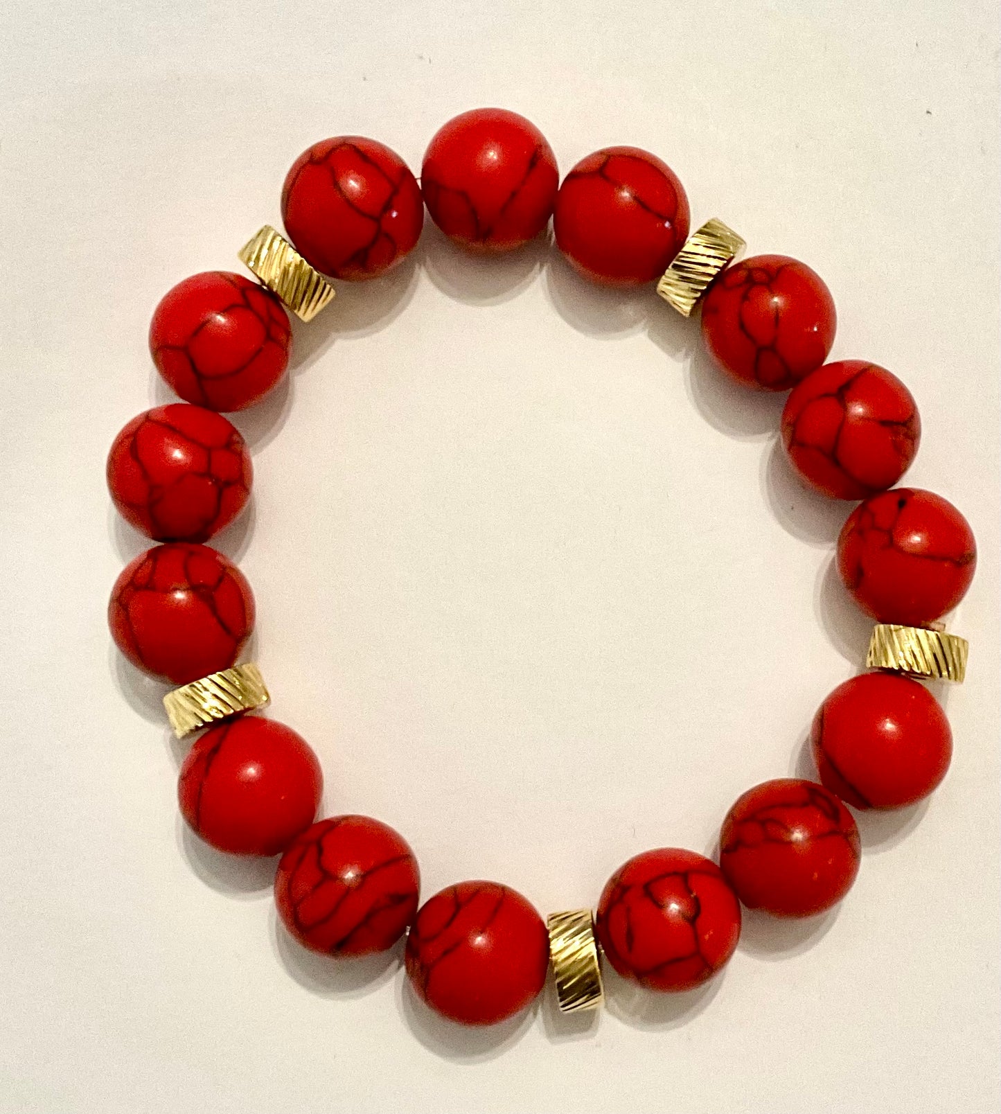 Red beaded bracelet with gold accents on a white background