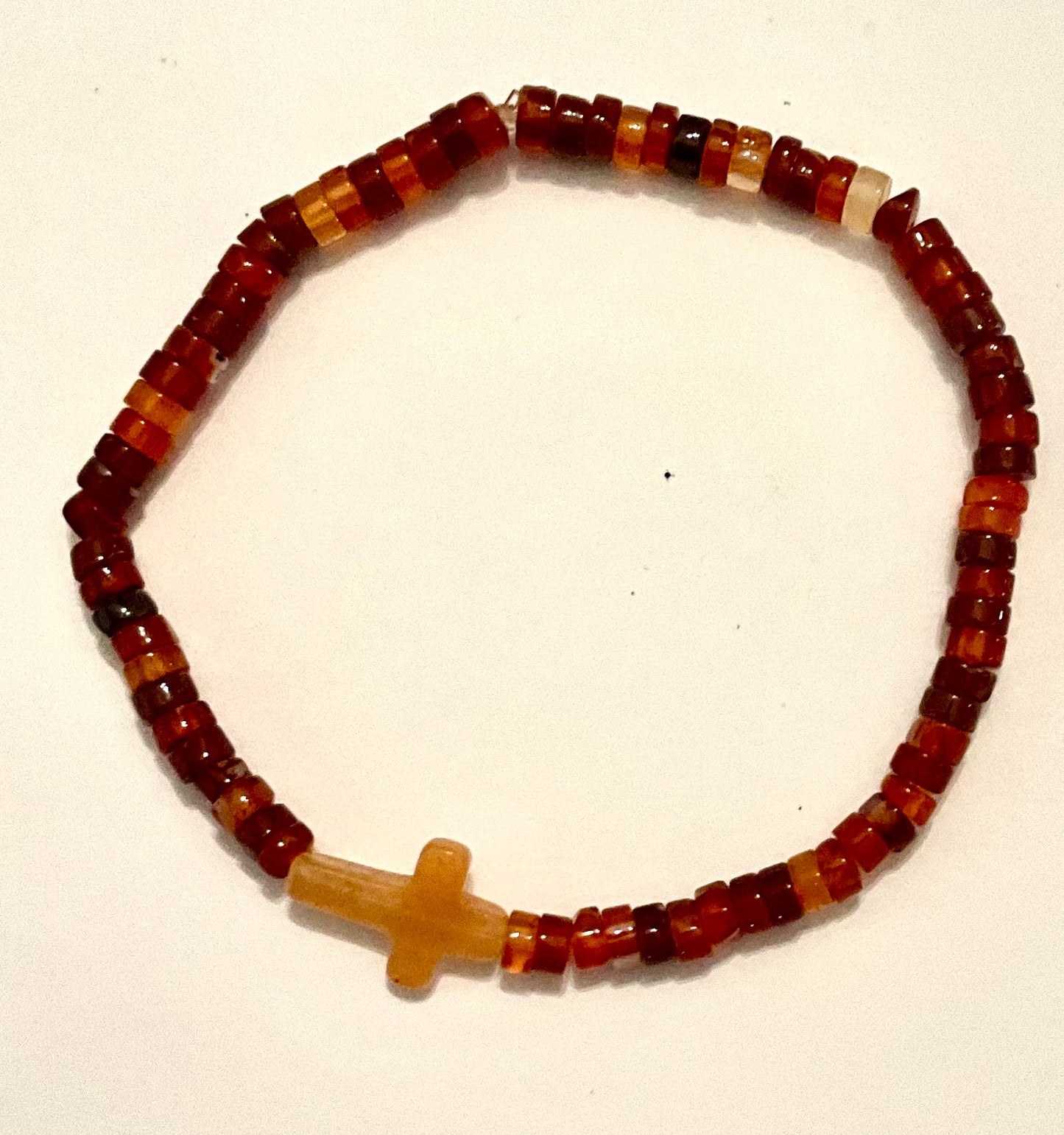 Beaded bracelet with a cross charm on a white background