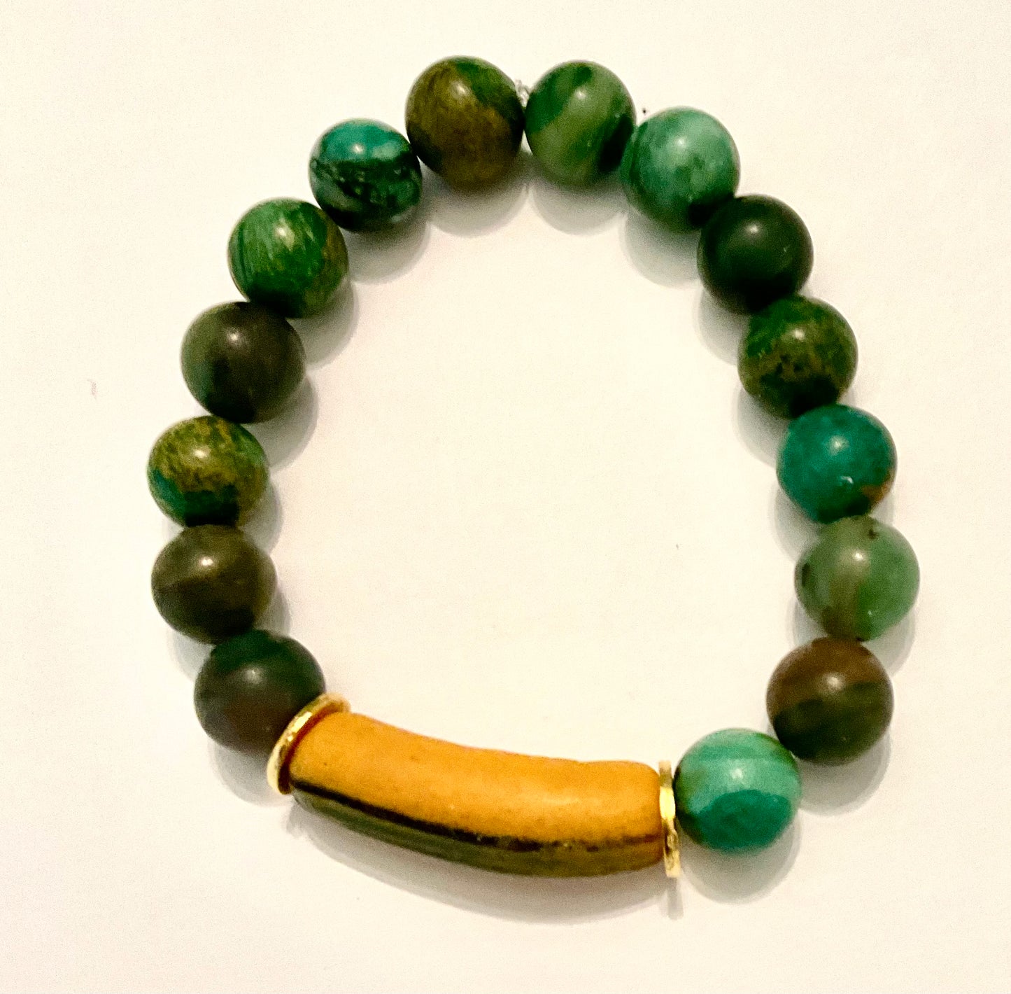 Green beaded bracelet with a wooden accent on a white background