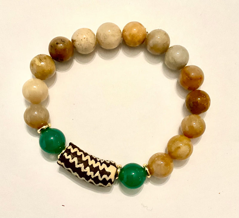 Beaded bracelet with green and brown beads on a beige background