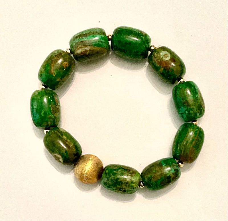 Green beaded bracelet with a gold accent on a white background