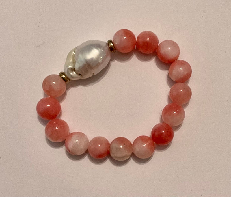 Bracelet with pink beads and a large white pearl on a light background
