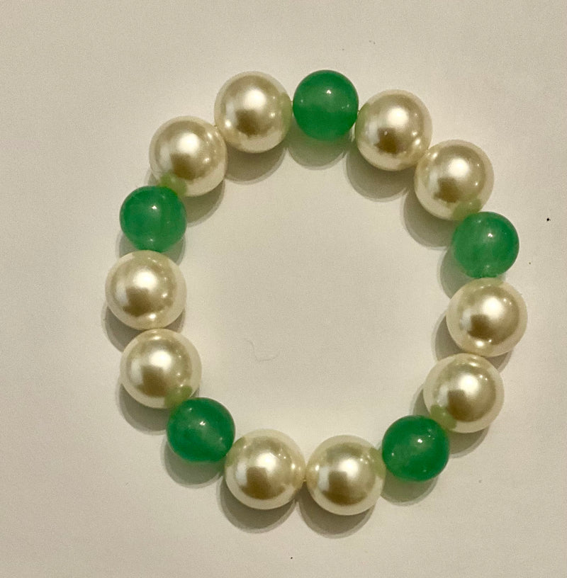 Bracelet with alternating green and pearl beads on a beige background