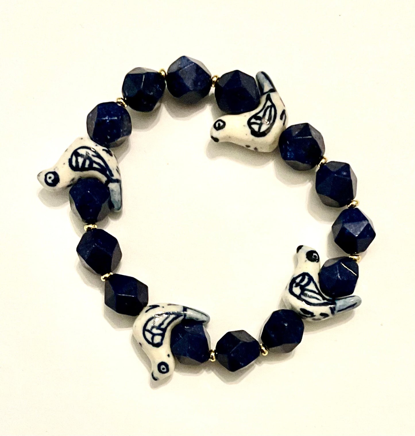 Bracelet with blue beads and white animal-shaped charms on a white background