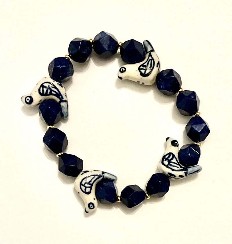 Bracelet with blue beads and white animal-shaped charms on a white background