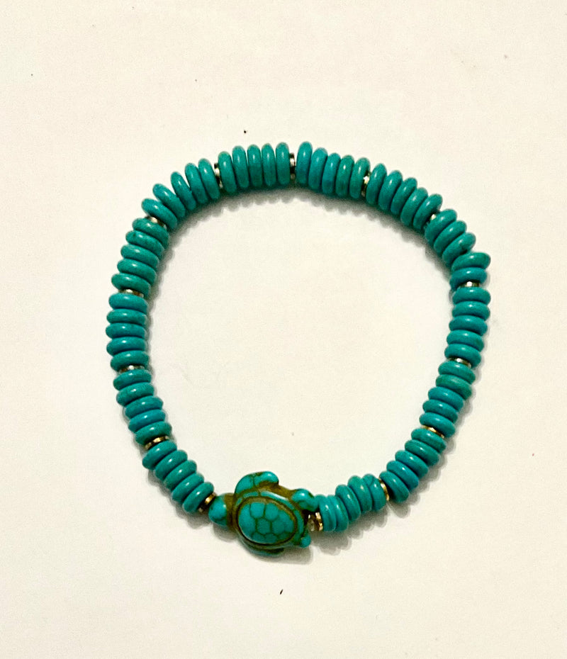 Turquoise beaded bracelet with a turtle charm on a light beige background