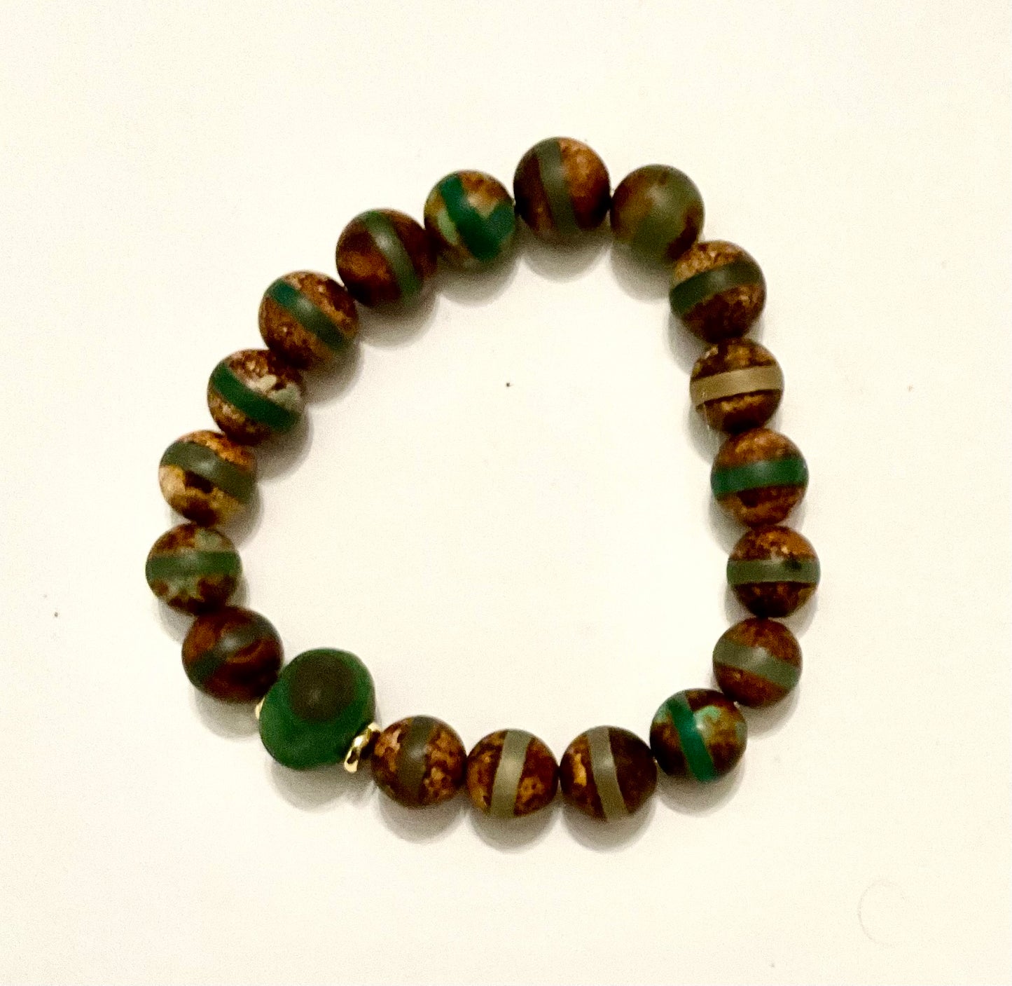 Beaded bracelet with green and brown pattern on a white background