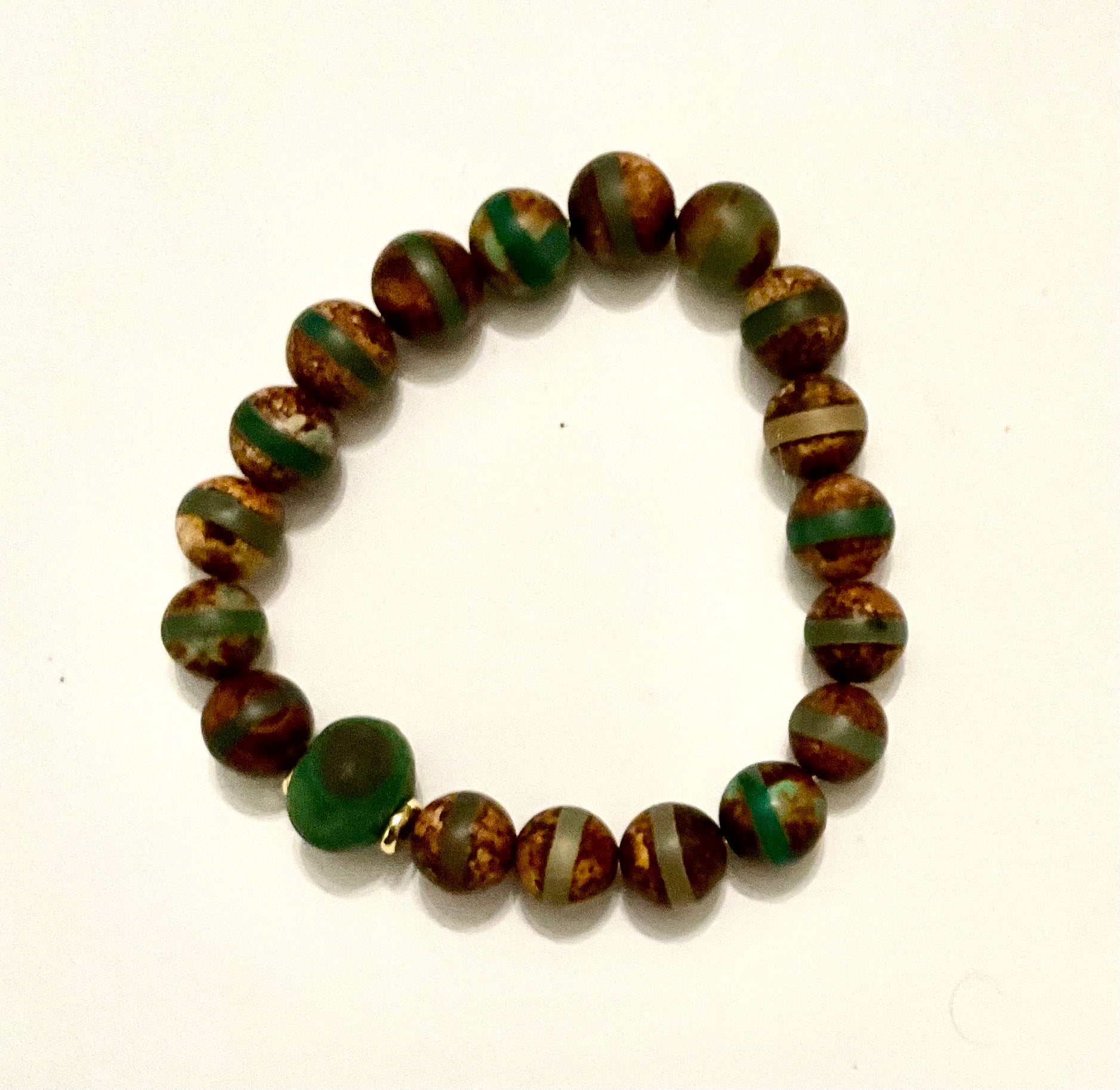 Beaded bracelet with green and brown pattern on a white background