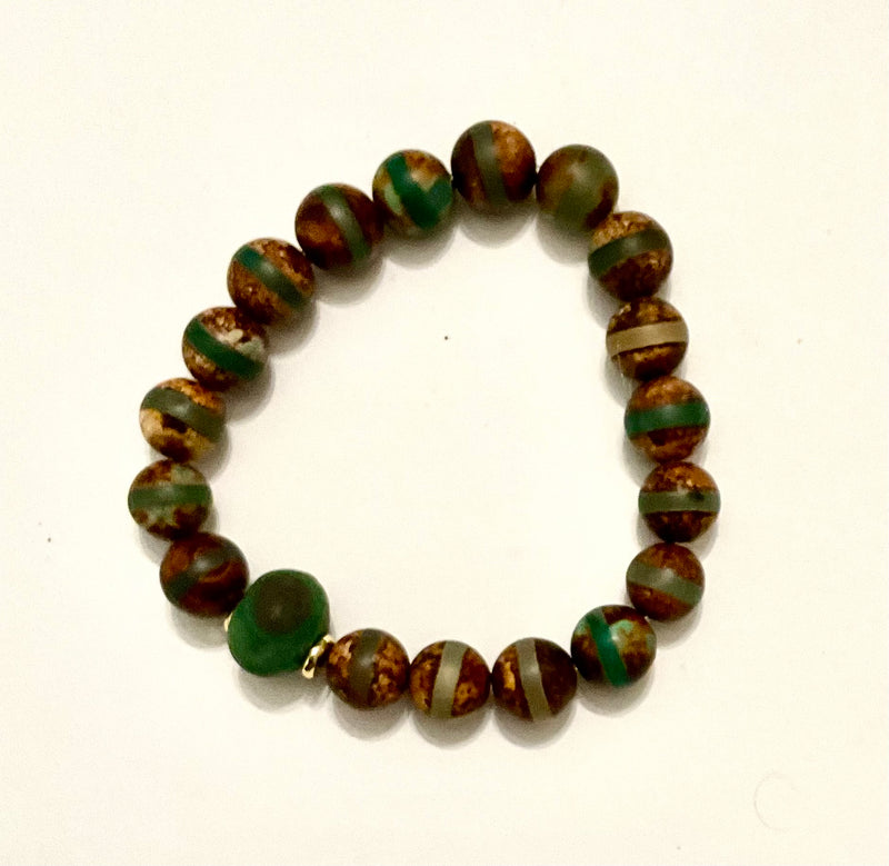 Beaded bracelet with green and brown pattern on a white background