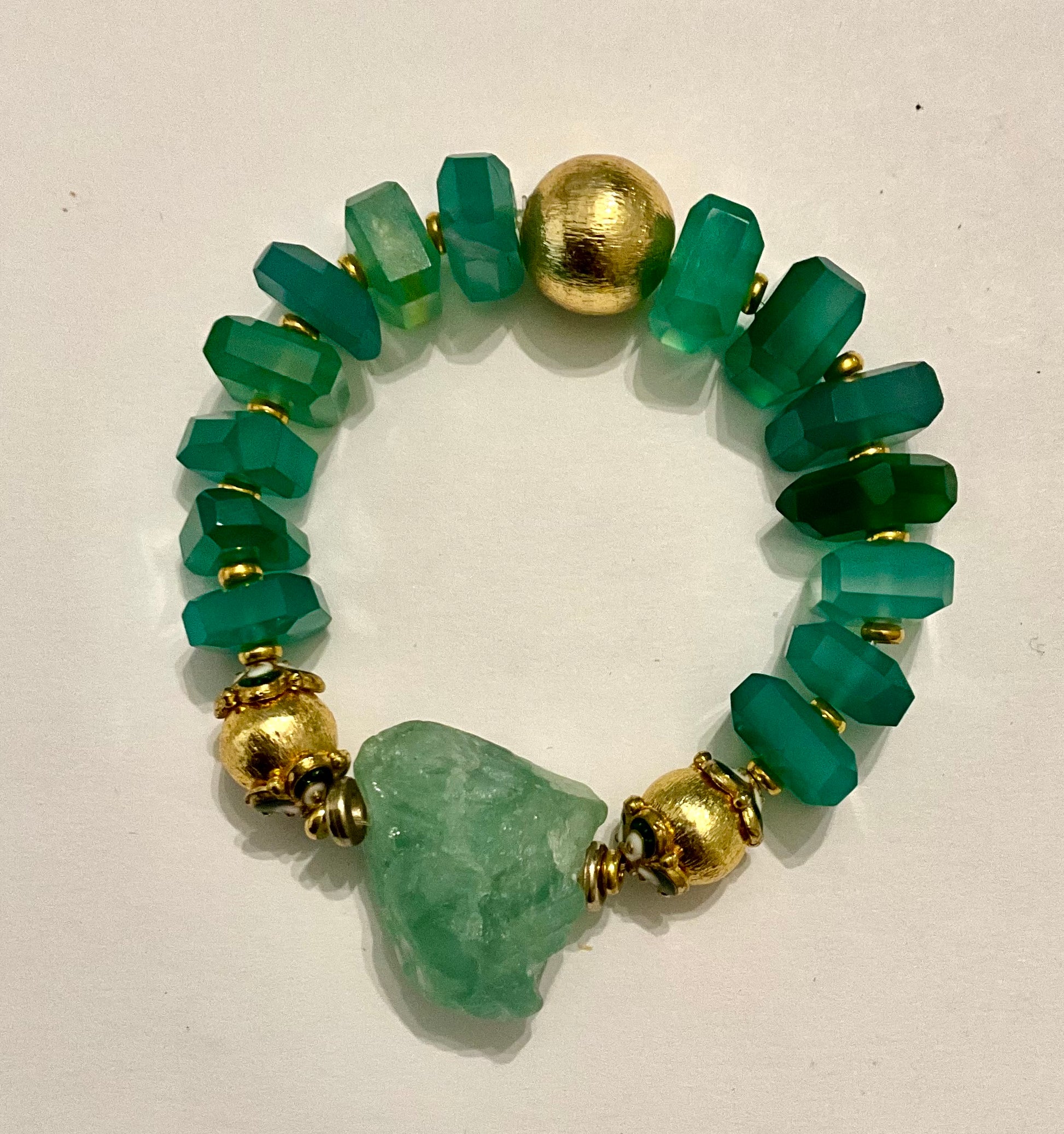Bracelet with green beads and gold accents on a white background