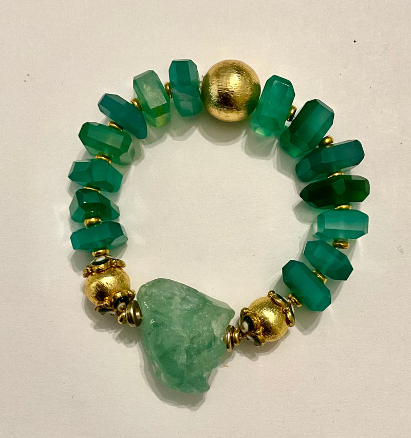 Bracelet with green beads and gold accents on a white background