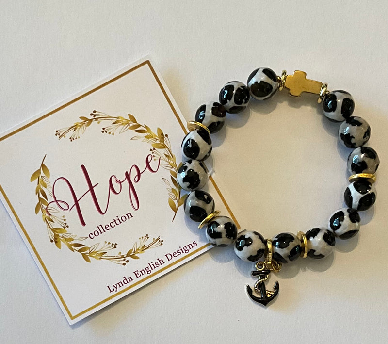 Bracelet with black and white pattern and gold accents on a 'Hope' collection card by Lynda English Designs.