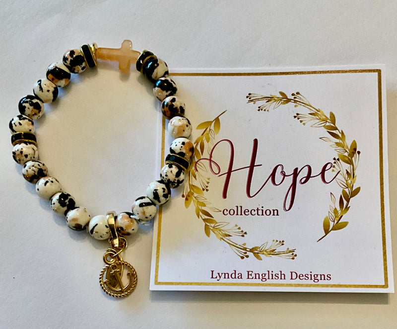 Bracelet with black and white beads and gold accents on a 'Hope' collection card by Lynda English Designs.