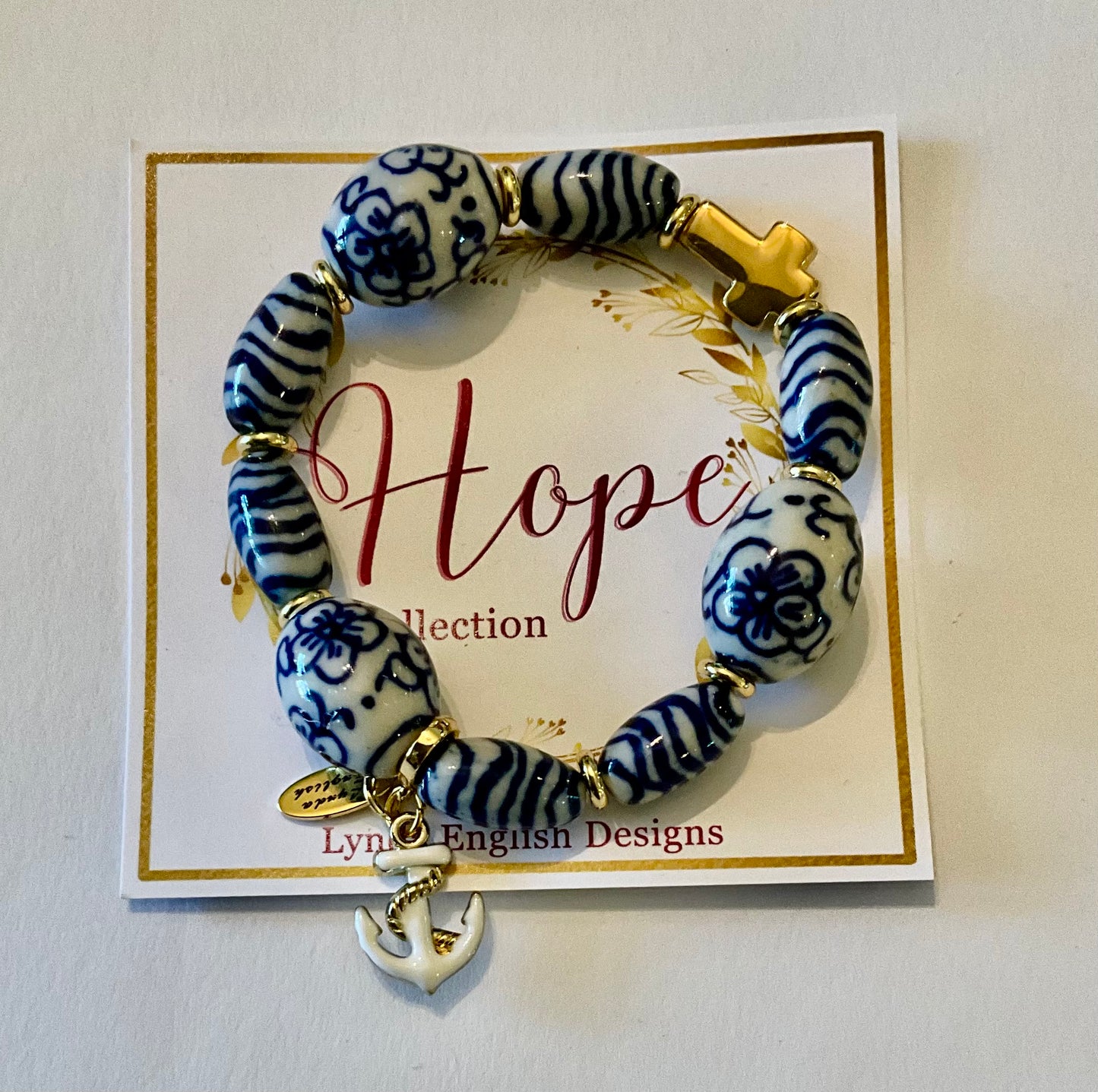 Bracelet with blue and white patterned beads and gold accents on a 'Hope' collection card.