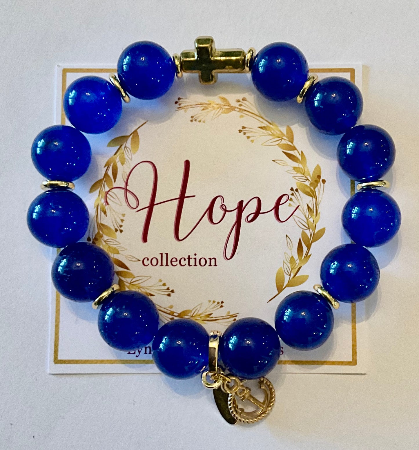 Blue beaded bracelet with a gold charm on a 'Hope collection' card.