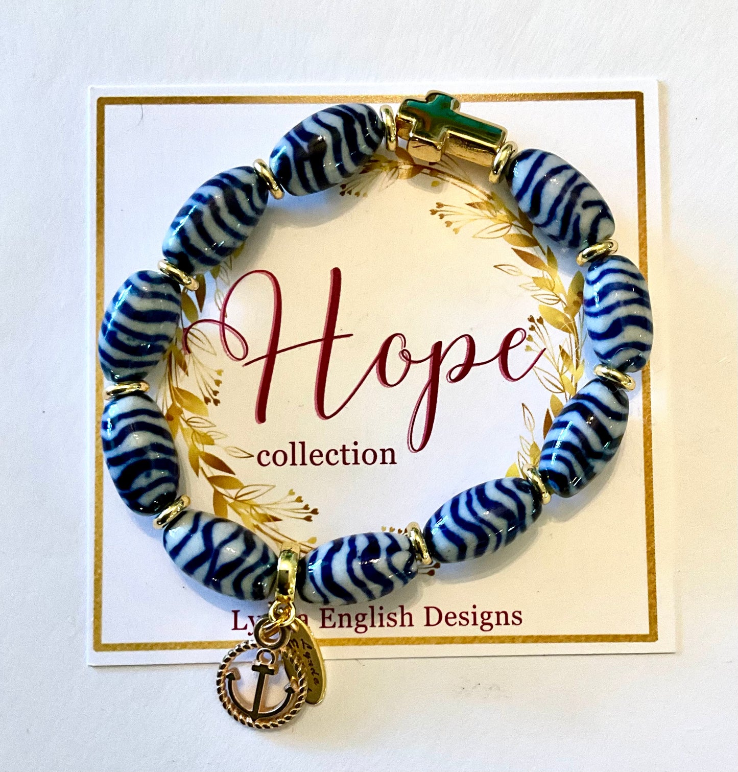 Blue and white beaded bracelet with gold anchor charm on a 'Hope' collection card.