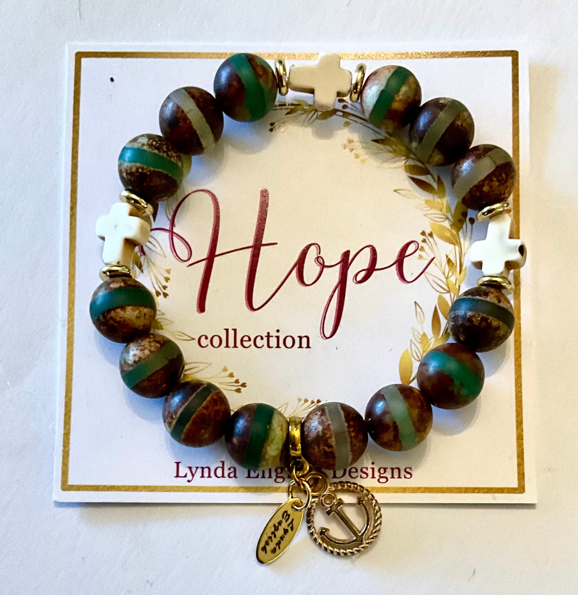 Bracelet with brown and green beads and gold accents on a 'Hope collection' card by Lynda English Designs.