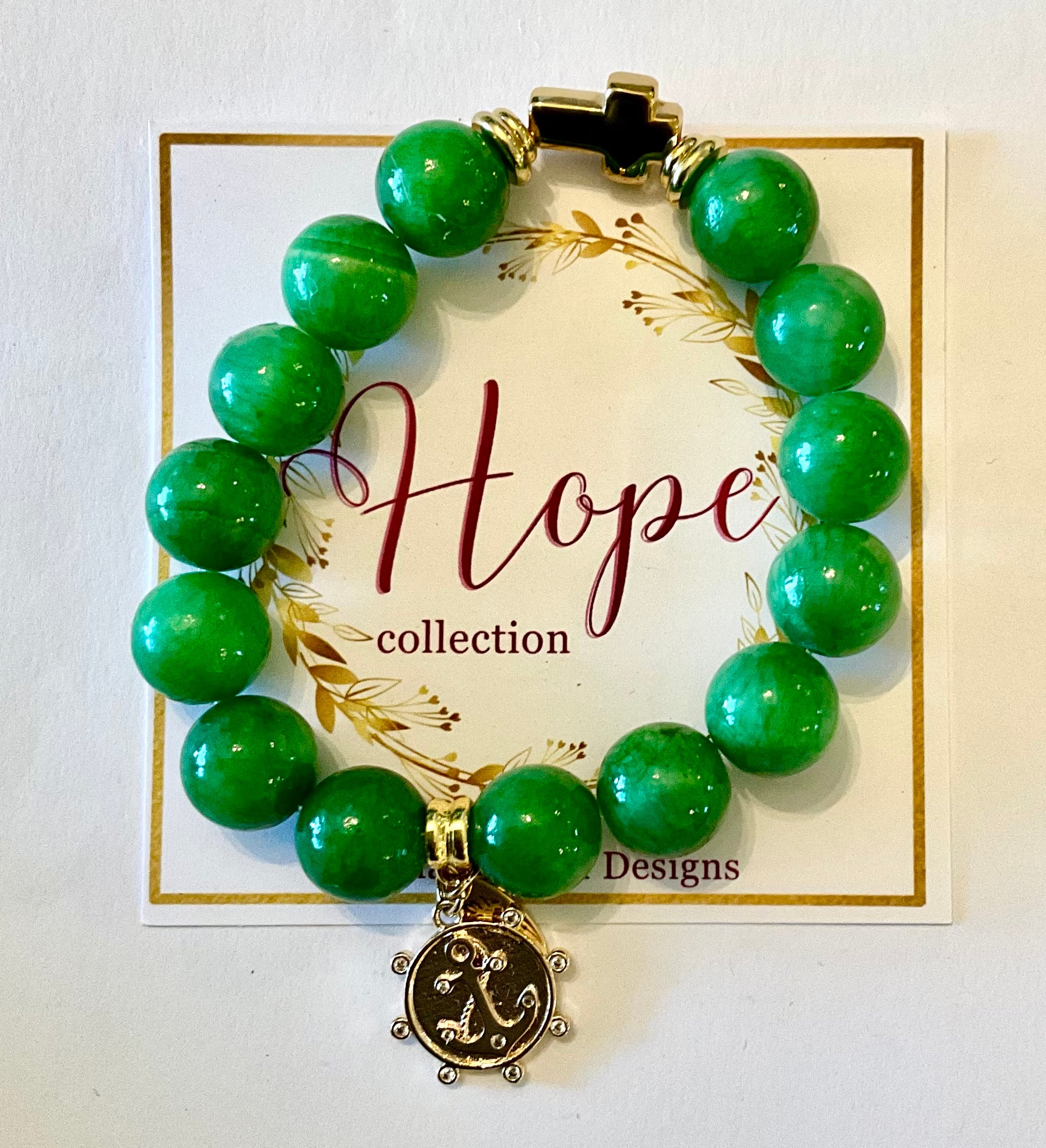 Green beaded bracelet with a gold charm on a 'Hope collection' card.