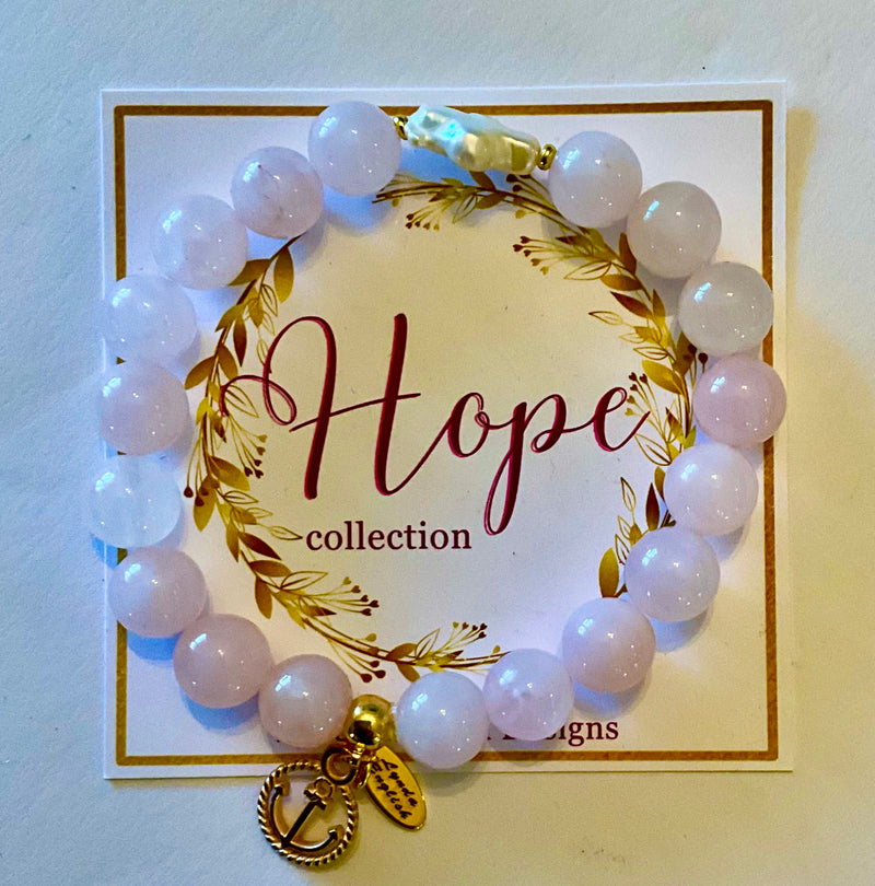 White beaded bracelet with a gold charm on a 'Hope collection' card.