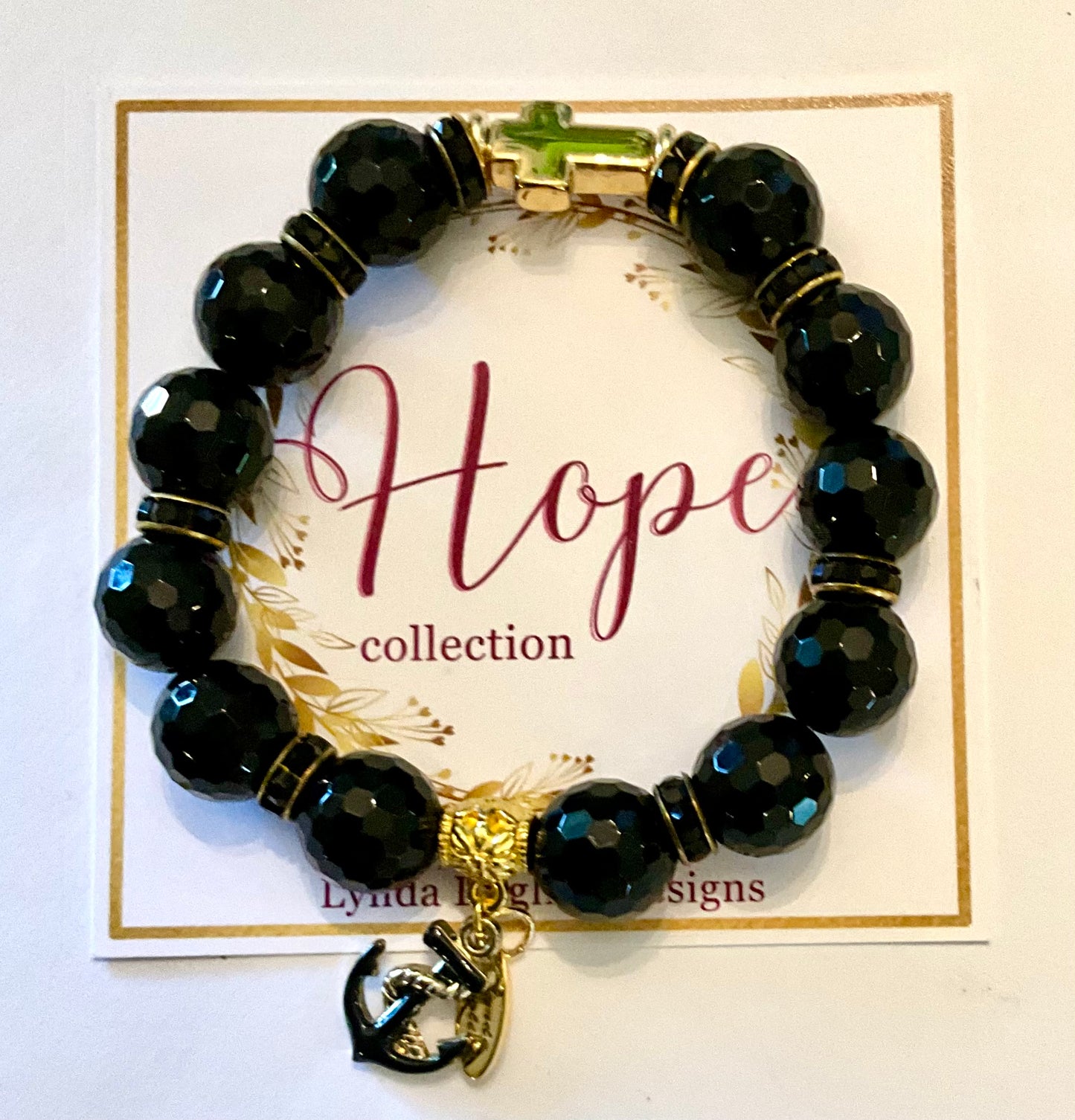 Black beaded bracelet with a gold anchor charm on a 'Hope collection' card.
