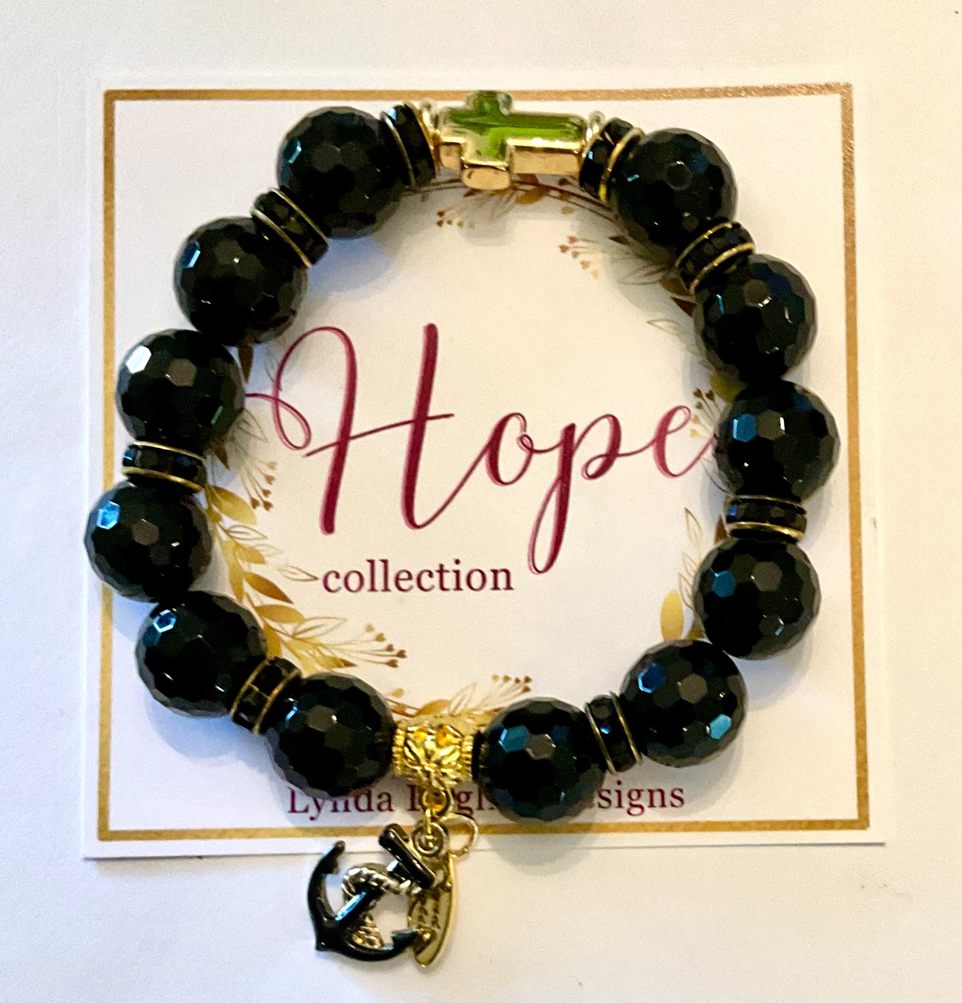 Black beaded bracelet with a gold anchor charm on a 'Hope collection' card.